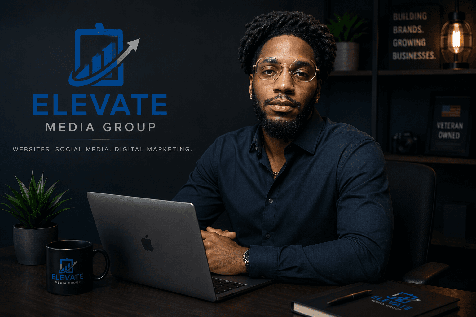 A professional Black man sits at a desk with a laptop for Elevate Media Group.